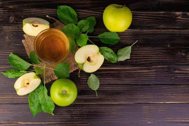 Suco de maçã e maçãs verdes em um fundo de madeiraLeitura planaCopie o espaço