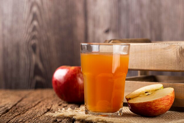 Suco de maçã e maçãs vermelhas em cima da mesa.