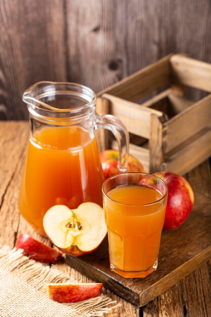 Suco de maçã e maçãs vermelhas em cima da mesa.