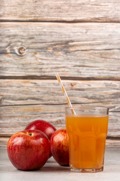 Foto suco de maçã e maçãs vermelhas em cima da mesa.
