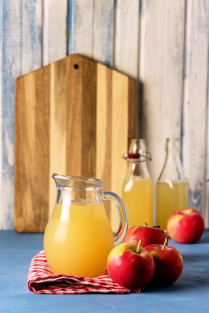 Suco de maçã orgânico saudável em um jarro e guardanapo de garrafa Maçãs vermelhas colheita vertical outono