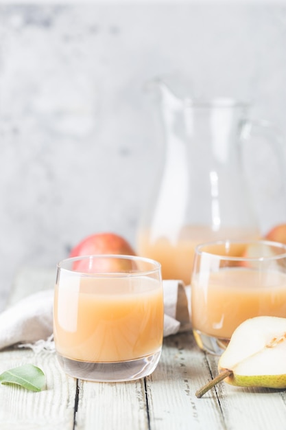 Suco de pêra fresco em um copo com frutas frescas em um fundo claro