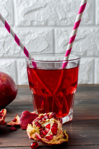 Suco de romã em vidro e romãs no fundo escuro de madeira velha