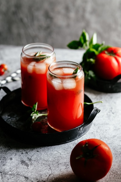 Suco de tomate com gelo em um copo em um fundo cinza