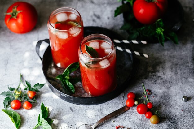 Suco de tomate com gelo em um copo em um fundo cinza