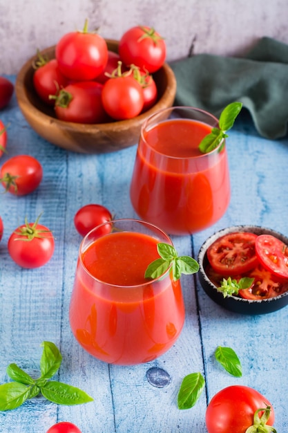 Suco de tomate com manjericão em copos e legumes na mesa bebidas caseiras orgânicas vertical