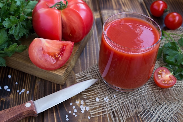 Suco de tomate e ingredientes no fundo de madeira rústica