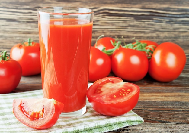 Suco de tomate e tomate fresco na mesa de madeira