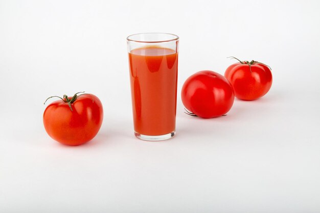 Suco de tomate e tomates frescos em um fundo branco