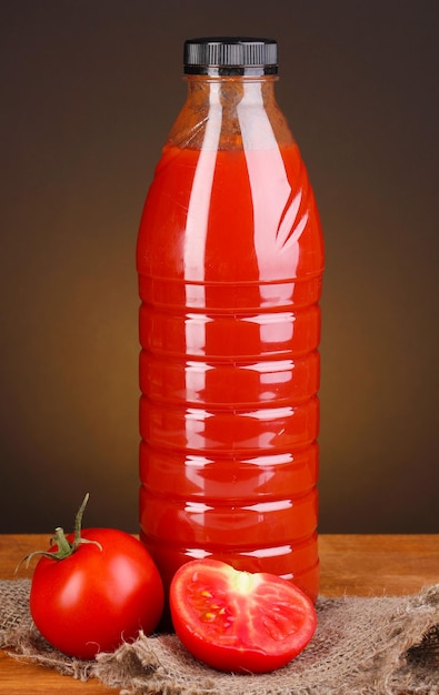 Suco de tomate em garrafa na mesa de madeira no fundo marrom