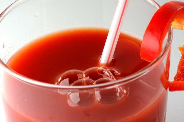 Suco de tomate em um copo com tubo de coquetel e close-up de uma fatia de pimentão