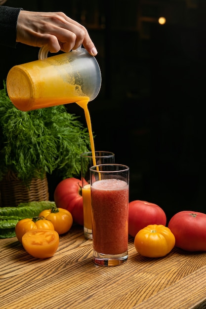 Foto suco de tomate em uma mesa perto dos tomates verdes, amarelos e vermelhos