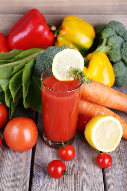 Suco de tomate em vidro e legumes frescos na mesa de madeira no fundo da parede de madeira