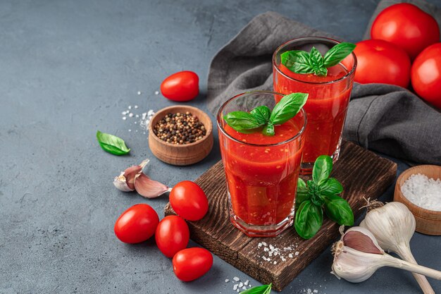 Suco de tomate fresco com sal de manjericão e especiarias em um fundo cinza