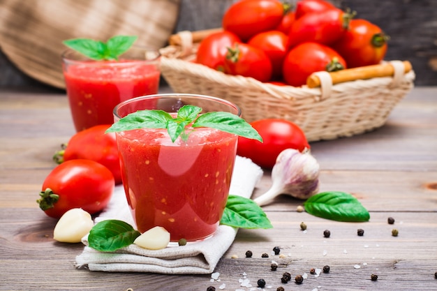 Suco de tomate fresco misturado com folhas de manjericão em copos em uma mesa de madeira
