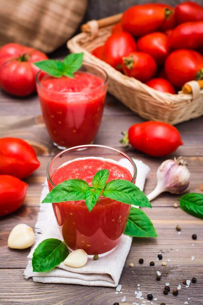 Suco de tomate fresco misturado com folhas de manjericão em copos em uma mesa de madeira
