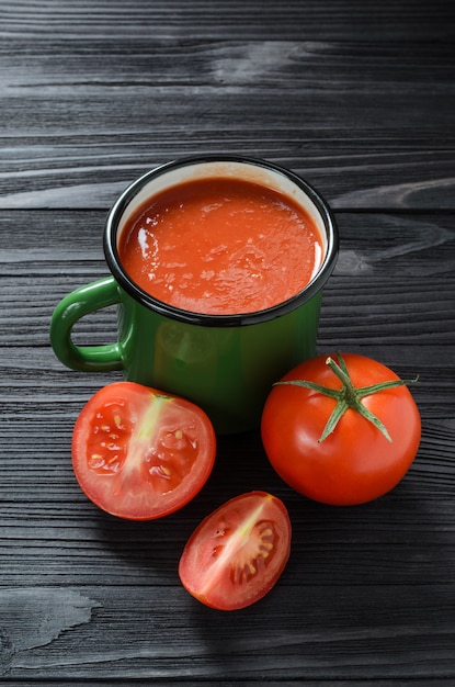 Suco de tomate na caneca verde do esmalte