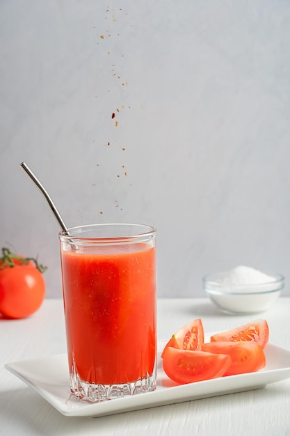 Suco de tomate salgado e refrescante servido em um copo com canudo de metal salpicado de pimenta malagueta