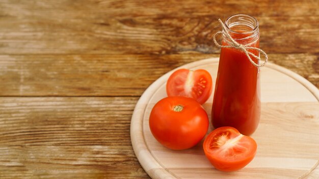 Foto suco de tomate, tomate fresco em fundo de madeira