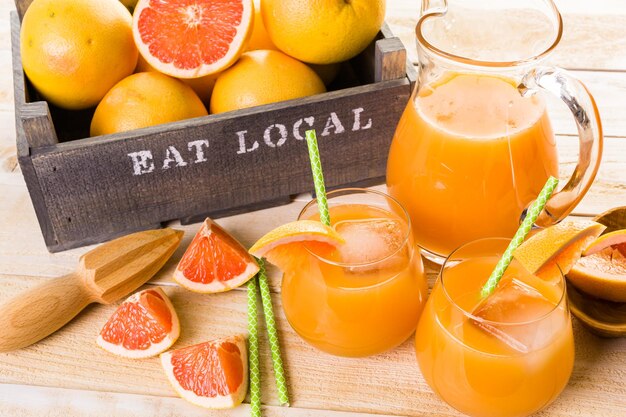 Suco de toranja vermelho rubi orgânico em um pequeno copo com gelo.