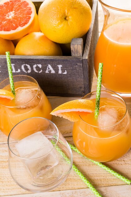 Suco de toranja vermelho rubi orgânico em um pequeno copo com gelo.