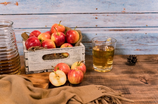 Suco fresco com maçãs vermelhas maduras orgânicas em caixa de madeira. Cornucópia da colheita de outono na temporada de outono.