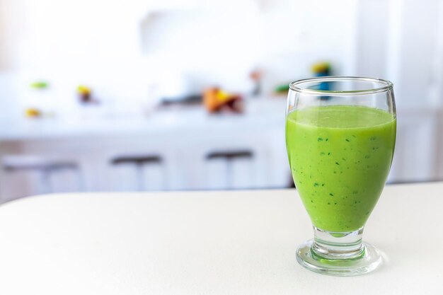 Suco verde muito saudável na mesa branca na cozinha