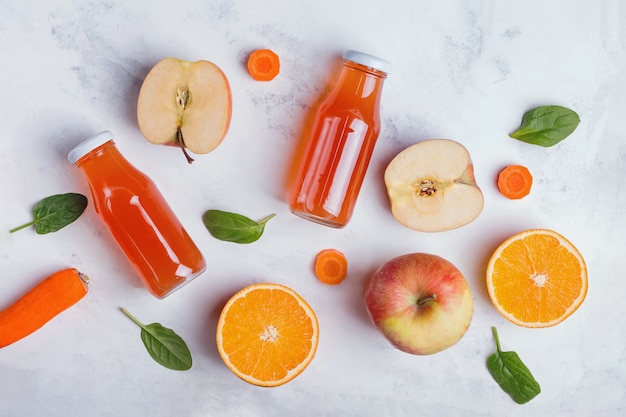 Sucos de frutas saudáveis, maçãs e laranjas na vista de mesa branca