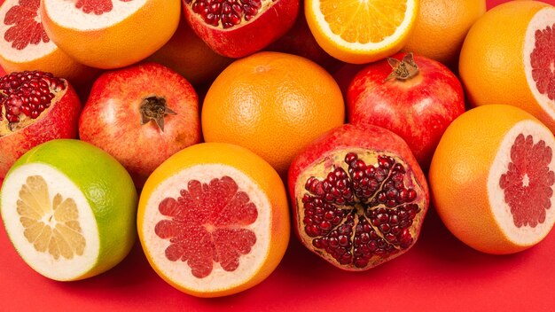 Suculenta toranja, laranja, romã, docinho cítrico na superfície vermelha.