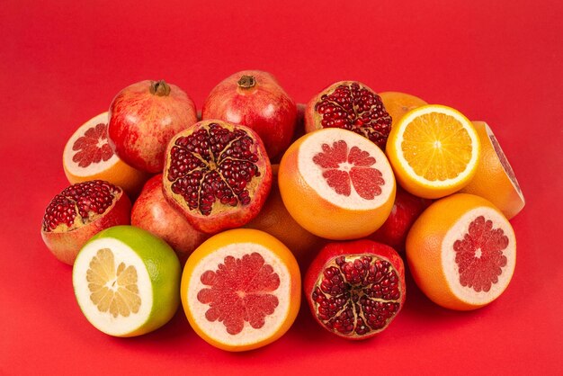 Suculenta toranja, laranja, romã, docinho cítrico sobre fundo vermelho.