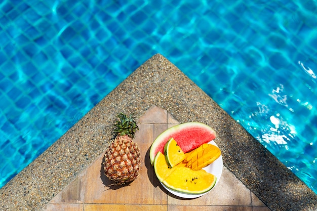 Suculentas frutas tropicais na beira da piscina com água azul cristalina. Descanso de fim de semana de luxo