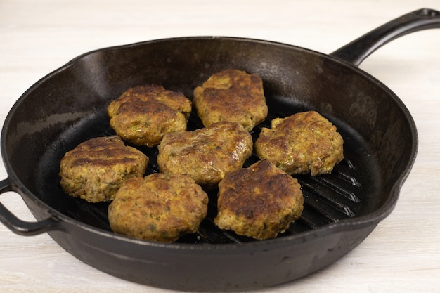 Suculento caseiro hambúrguer carne costeleta de carne, porco, frango, peru na frigideira de ferro fundido preto na mesa branca. conceito de dieta cetogênica, carnívora e com baixo teor de carboidratos.