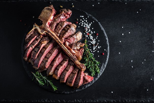 Suculento chuletón grande a la parrilla con guarnición sobre tabla de cortar.