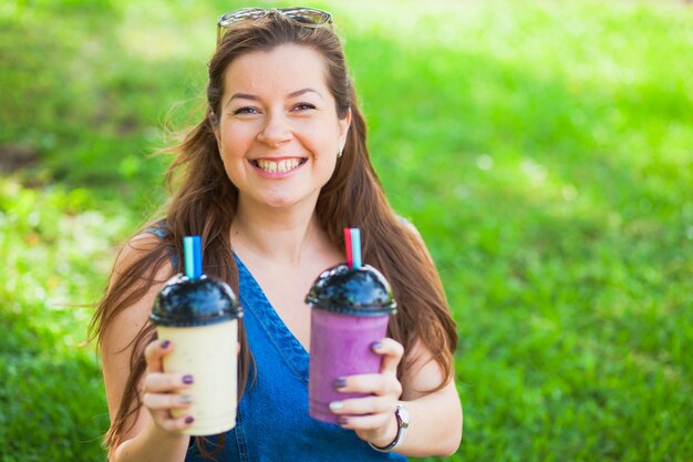 Suculento fresco resfriado saudável delicioso smoothie milkshake jovem mulher beber ao ar livre em um dia quente de verão ensolarado. Dieta saudável, perda de peso, conceito de vitaminas.