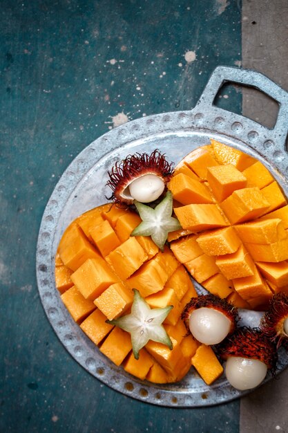 Suculento, manga madura, rambutan e canhão em uma placa de metal