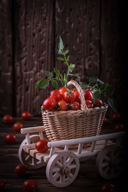 Suculento tomate vermelho na cesta na mesa de madeira