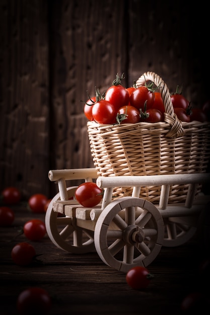 Suculento tomate vermelho na cesta na mesa de madeira