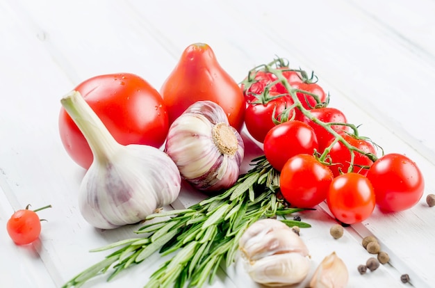 suculentos tomates orgânicos cereja vermelhos, alecrim, alho e especiarias na mesa