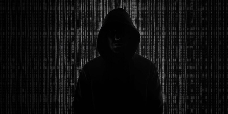 Foto en una sudadera con capucha sentado en su ordenador hacker