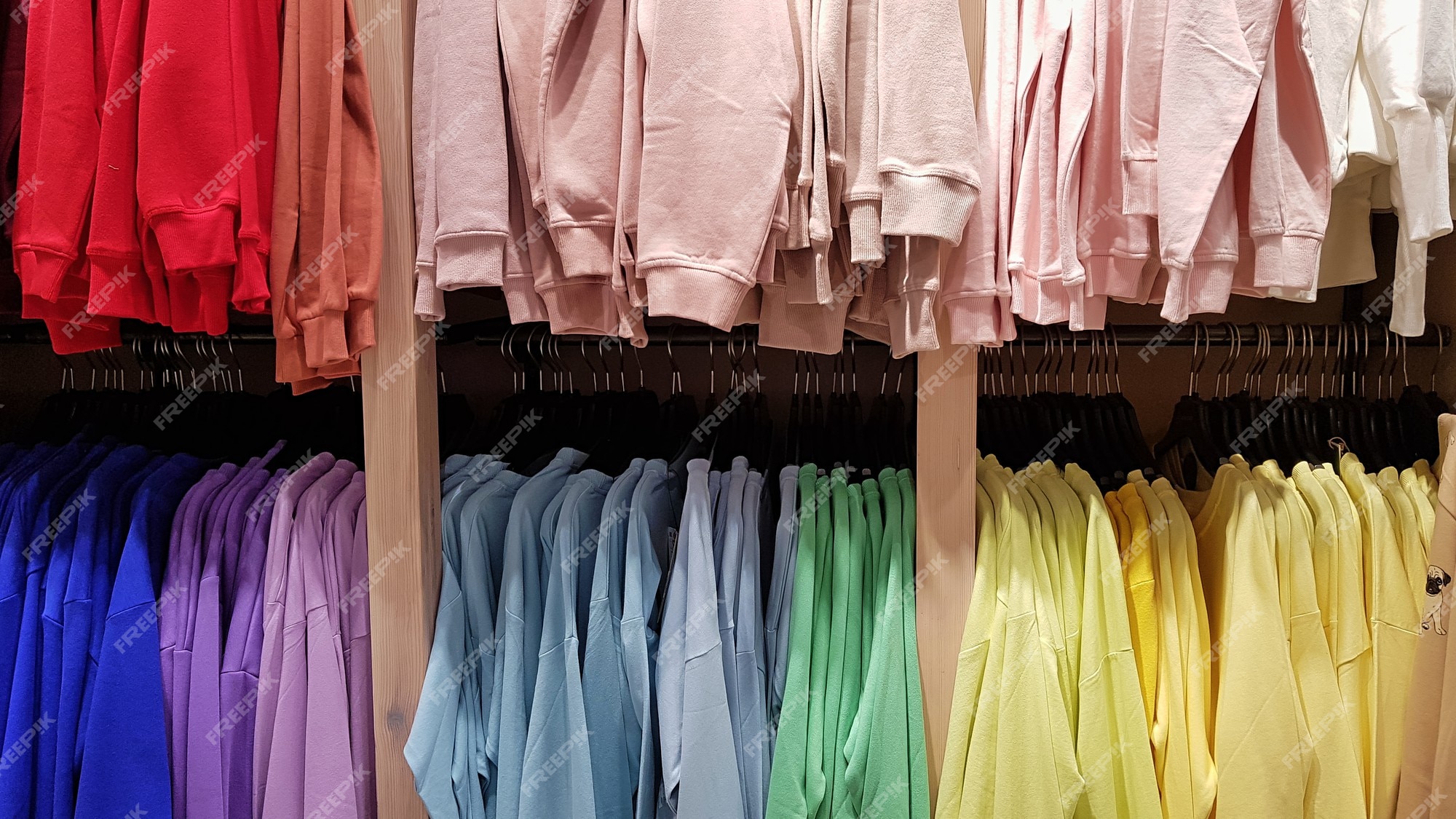 Sudaderas de colores brillantes colgadas en una tienda de moda. primer plano de varios colores amarillo, rojo, | Foto Premium