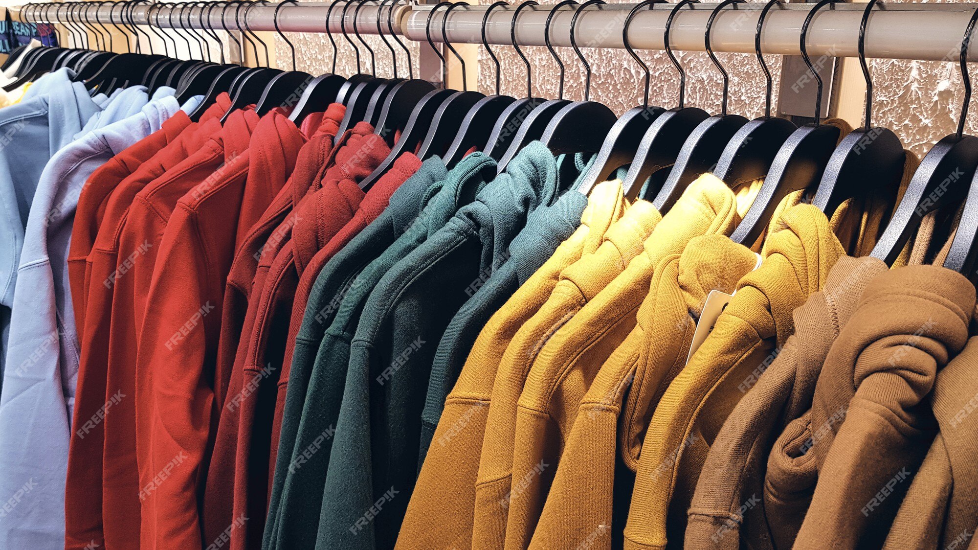 Sudaderas de colores brillantes colgadas en una tienda de moda. primer plano de varios colores amarillo, rojo, | Foto Premium