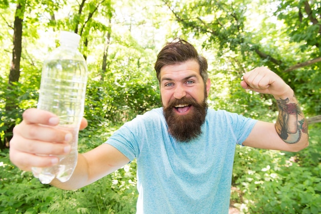 Sin sudar. hombre barbudo lleno de energía. hombre moreno barbudo con botella de agua en el bosque. Brutal morena barbudo bebe agua. chico maduro con barba en madera. caluroso día de verano. sentir sed