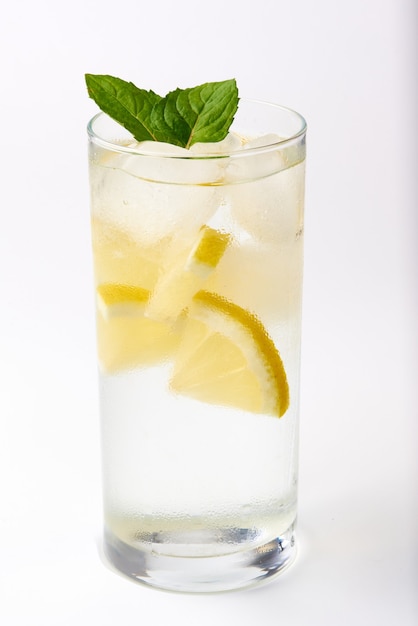 Un sudoroso vaso con limón y menta sobre un fondo blanco.