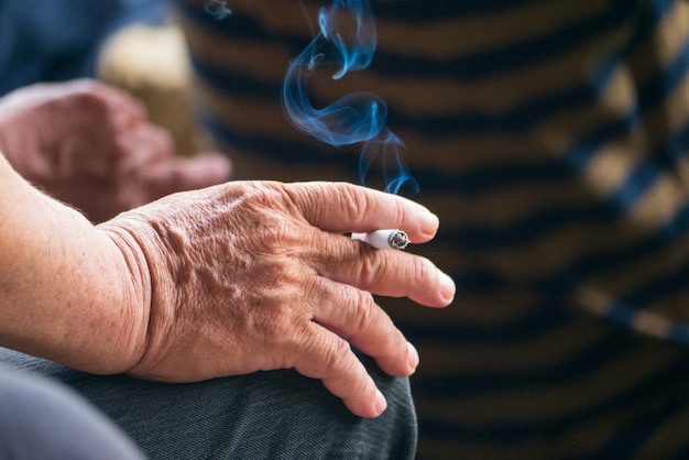 Süchtig machender Raucher mit Hand halten Zigarettentabak Zigarre Lebensstil mit Rauch unter Nichtraucherkampagne