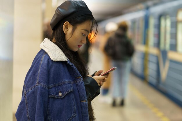 Süchtig vom Telefon, chinesisches Mädchen, achten Sie nicht auf den ankommenden Zug auf der Plattform scrollen Sie in den sozialen Medien