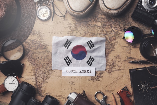 Foto südkorea-flagge zwischen dem zubehör des reisenden auf alter weinlese-karte. obenliegender schuss