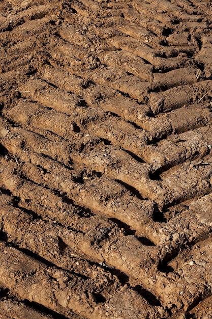 Suelo bien arado en el campo agrícola antes de la siembra de plantas, un primer plano de las huellas del tractor dejadas en el suelo