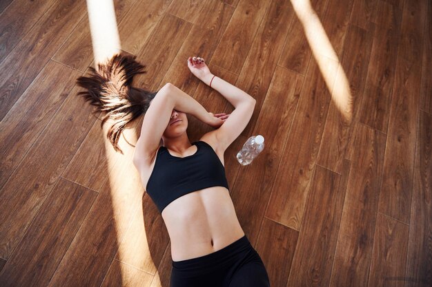 En el suelo iluminado por haces de luz. Joven deportiva en ropa deportiva descansando.