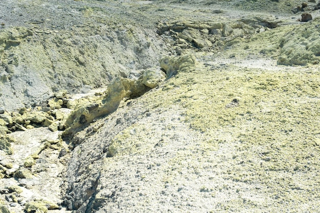 Suelo de tefra con depósitos amarillos de minerales sulfurosos en el área de gases volcánicos en el campo solfatárico