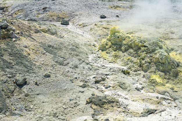 Suelo de tefra con depósitos amarillos de minerales sulfurosos en el área de gases volcánicos en el campo solfatárico